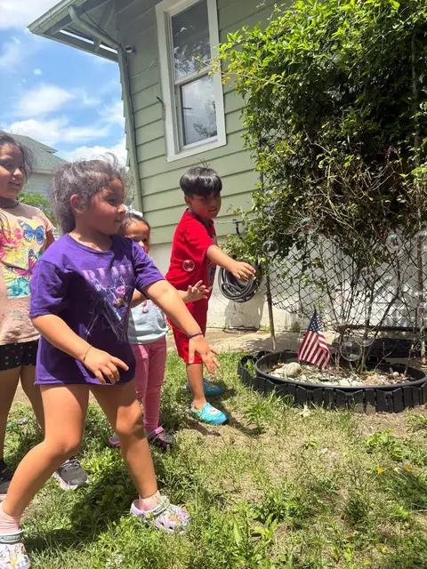 School-age children chase bubbles in the backyard
