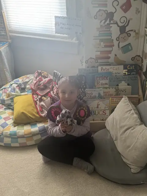 A kindergartner sits in the reading corner with bilingual books
